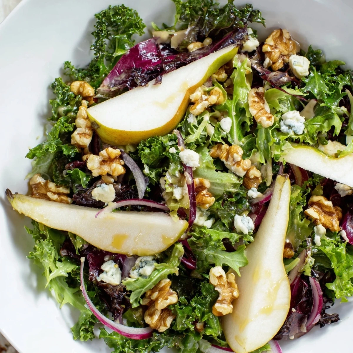 Winter Green Salad with Pear and Walnuts served in a white bowl, perfect light appetizer side for a contemporary American dinner.