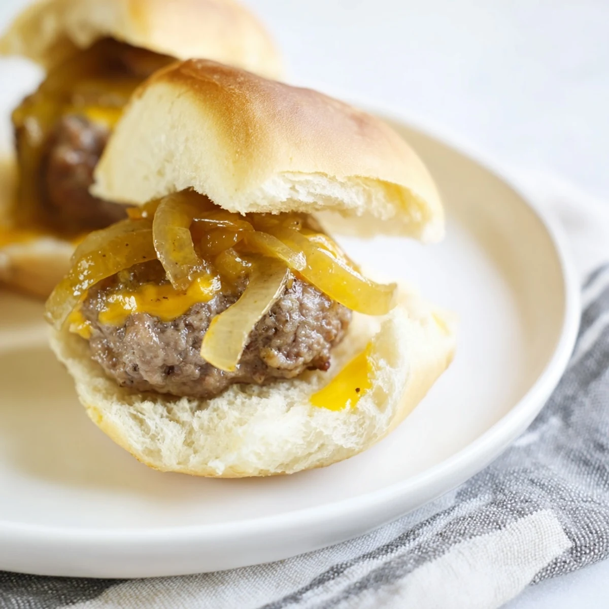 Juicy beef sliders with caramelized onions and melted cheese on toasted buns.