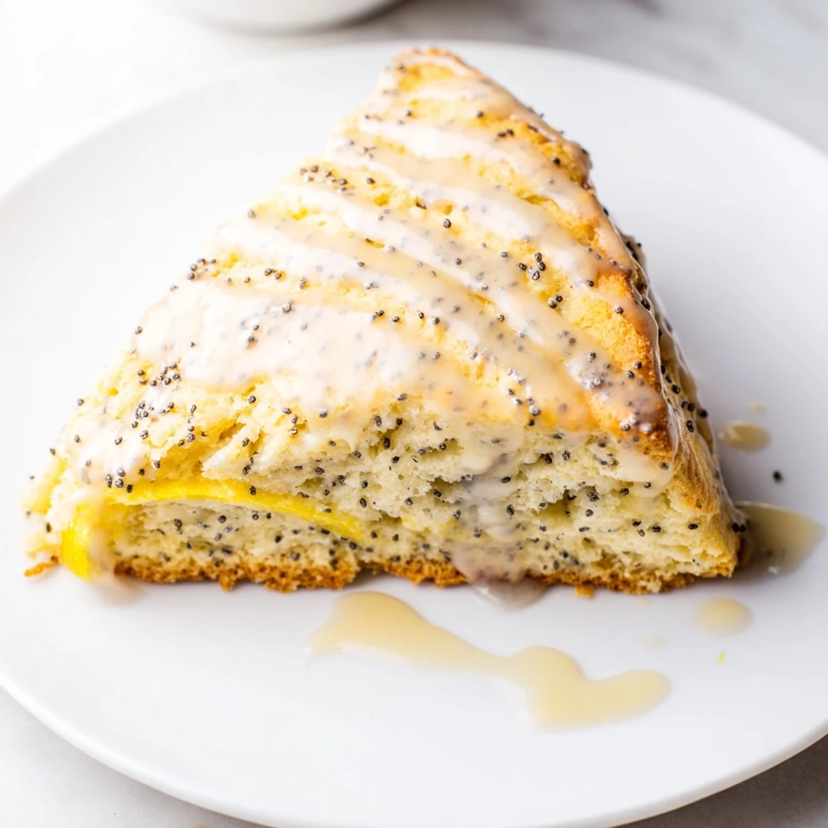 Homemade Lemon Poppy Seed Scones served warm on a plate with a cup of tea.