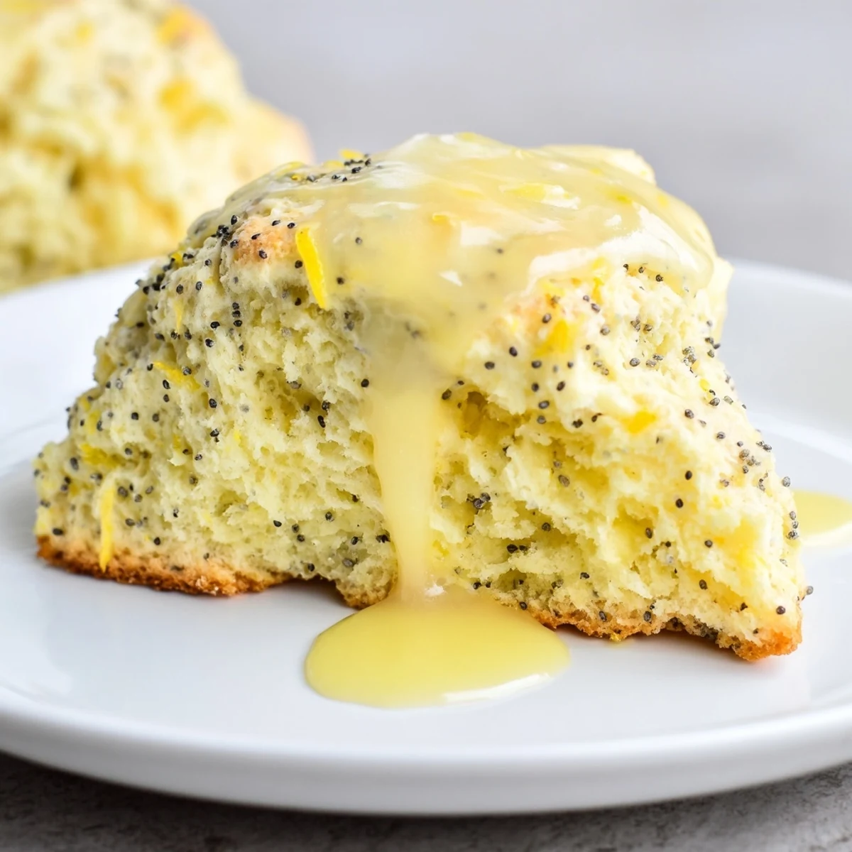 Freshly baked Lemon Poppy Seed Scones with a shiny glaze sitting on a rustic wire rack.