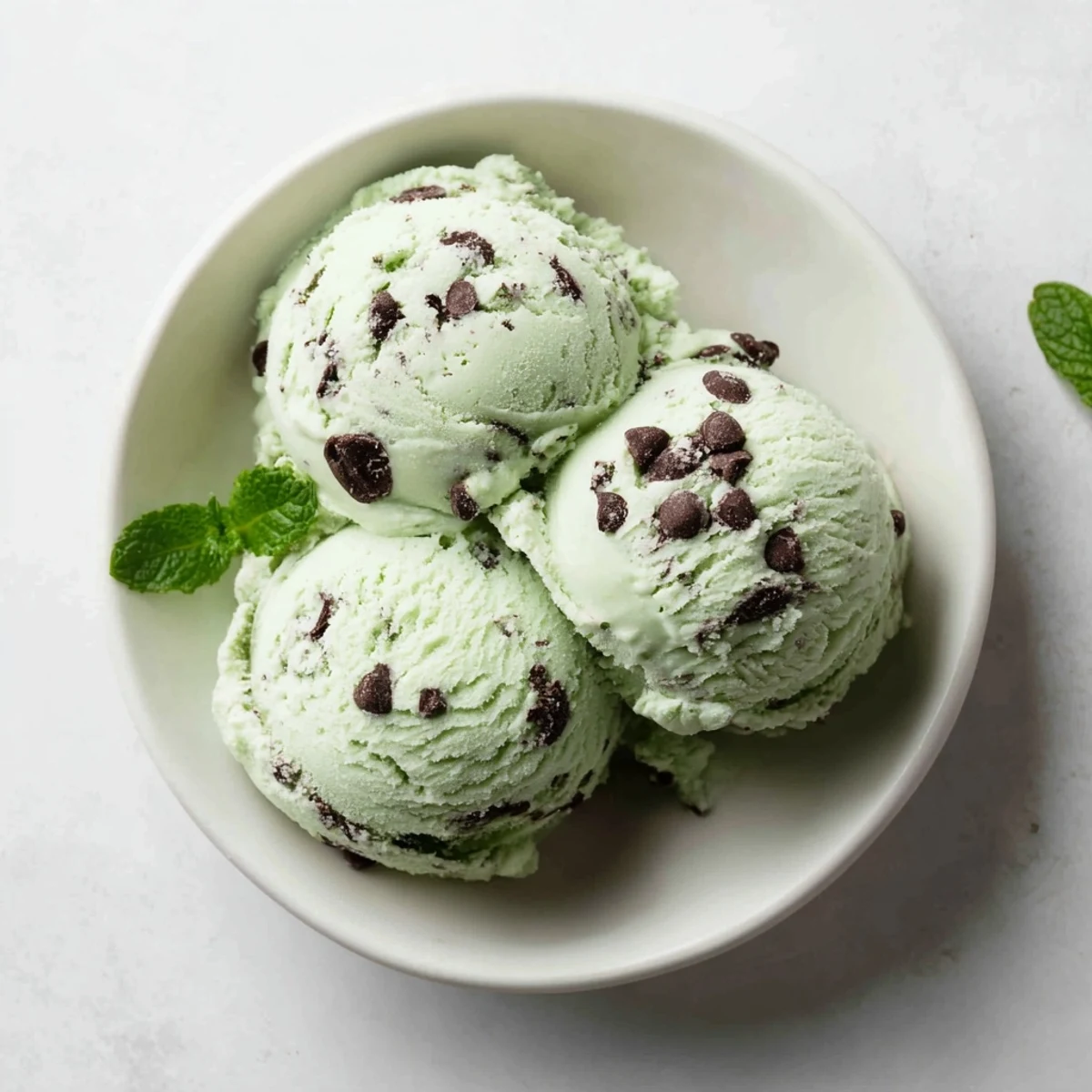 A close-up of Green Mint Chocolate Chip Ice Cream in a waffle cone, minty and cold.