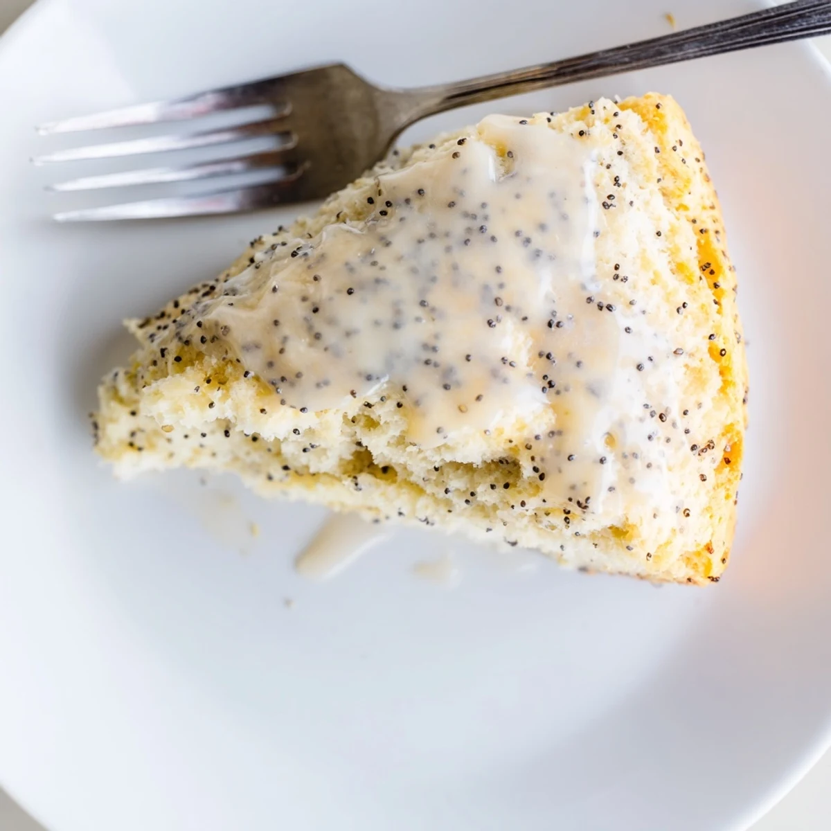 Warm Lemon Poppy Seed Scones with glaze drizzled over, served with tea on a breakfast table.