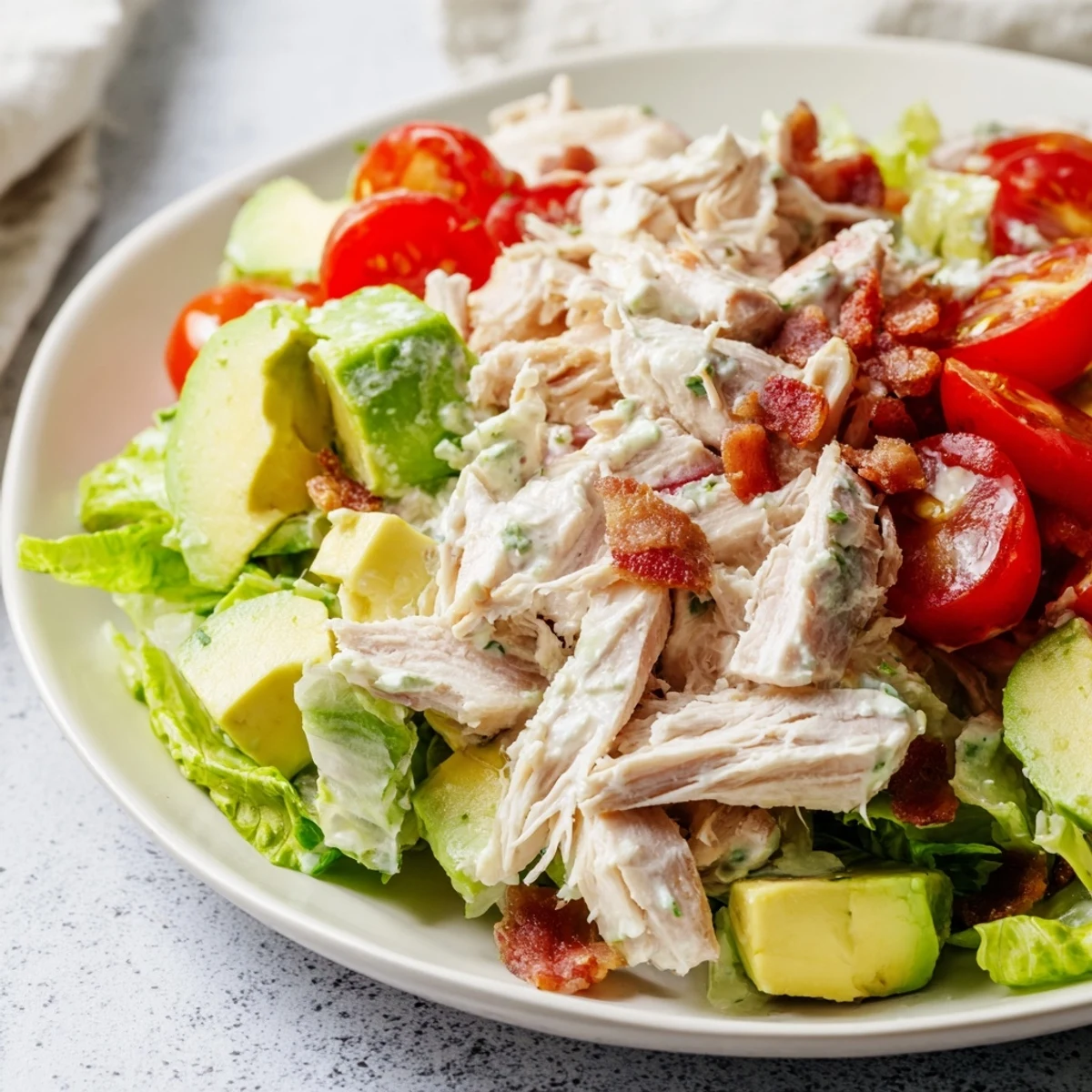 Fresh BLT Chicken Salad served in a white bowl with lemony Greek yogurt dressing drizzled.