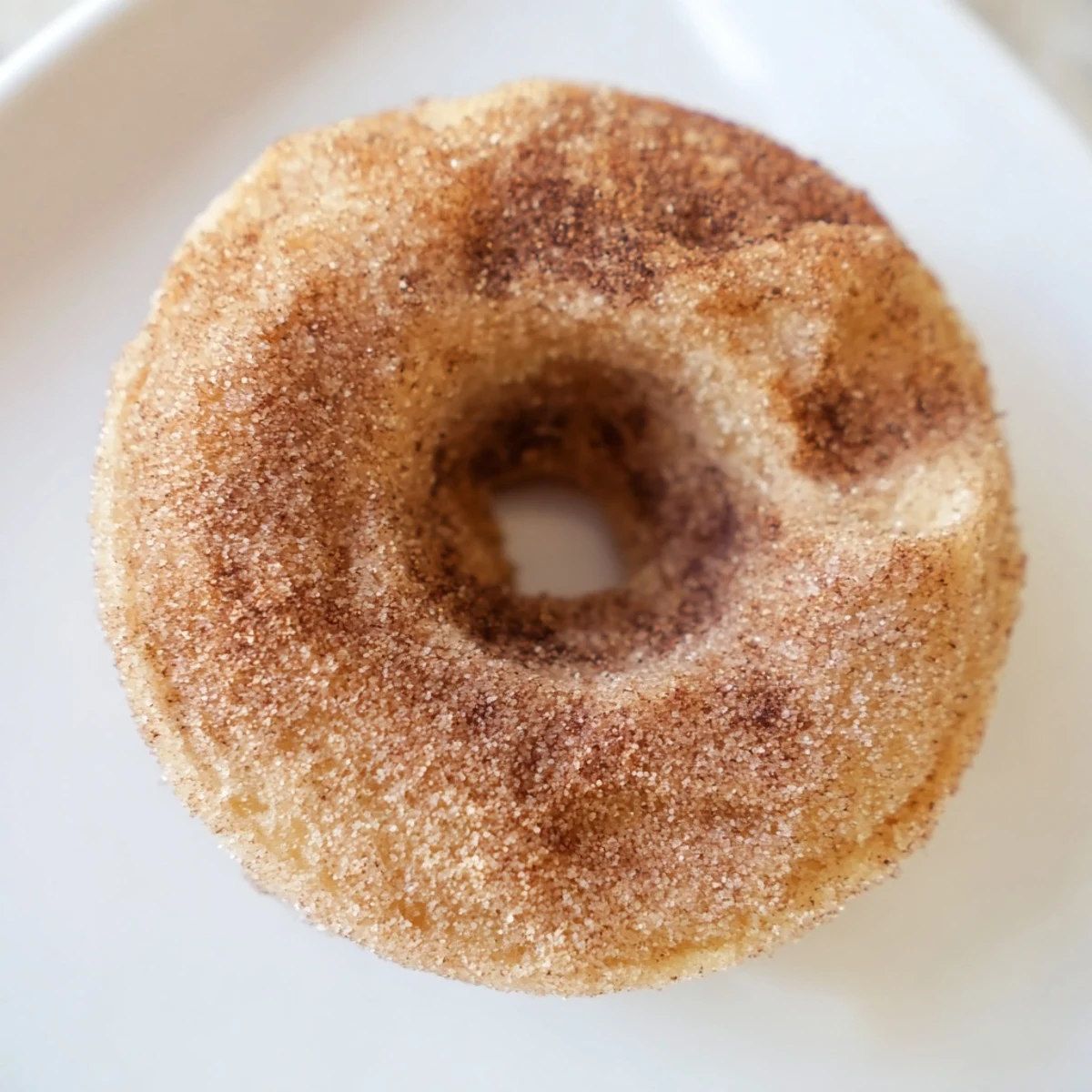 A close-up of warm Delicious Baked Cinnamon Sugar Donuts You Can’t Resist, glistening with melted butter and spice.