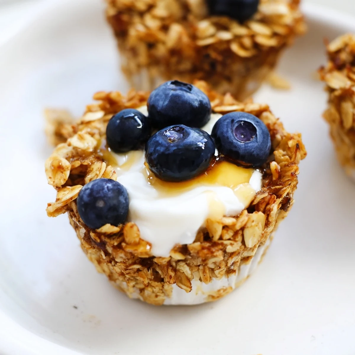 Golden-brown Baked Oatmeal Cups with Greek Yogurt topped with fresh blueberries sit on a cooling rack, ready for breakfast.