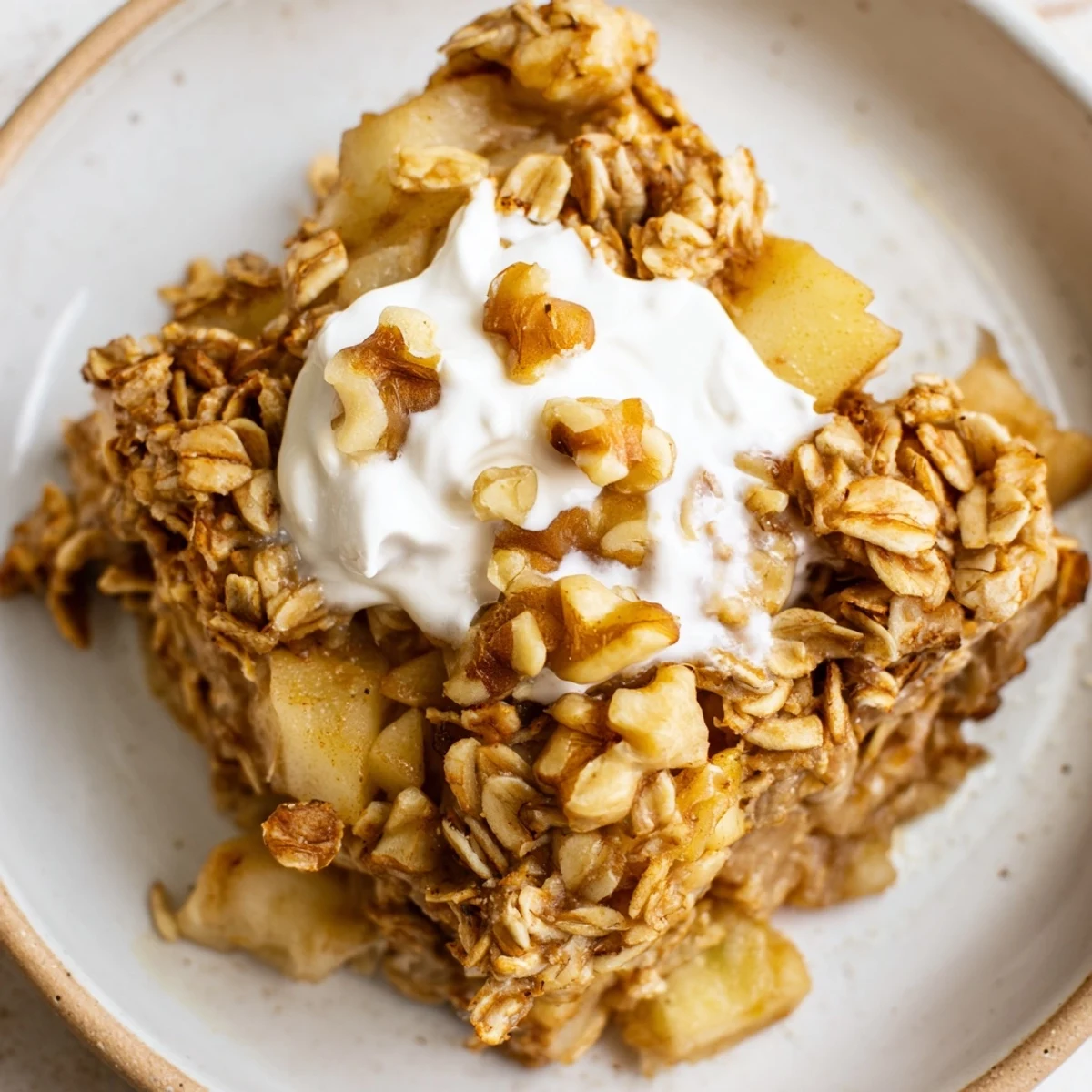 A close-up of Baked Apple Oatmeal with Greek Yogurt reveals a moist, spiced oat base and a thick yogurt topping.