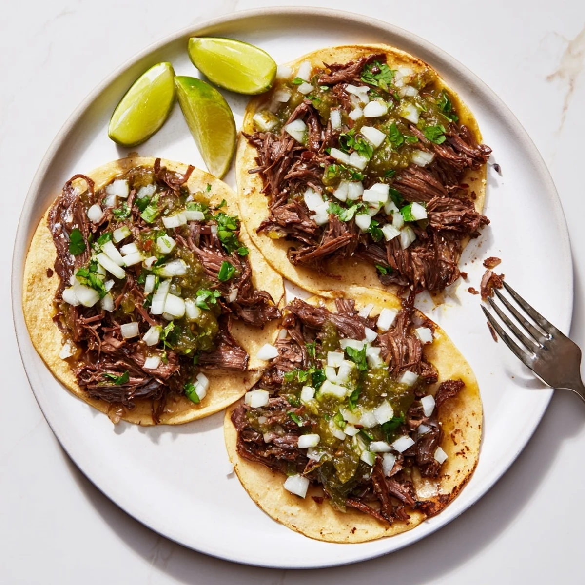 Tender shredded Beef Cheek Tacos on warm corn tortillas with fresh cilantro, diced onion, and zesty salsa verde.