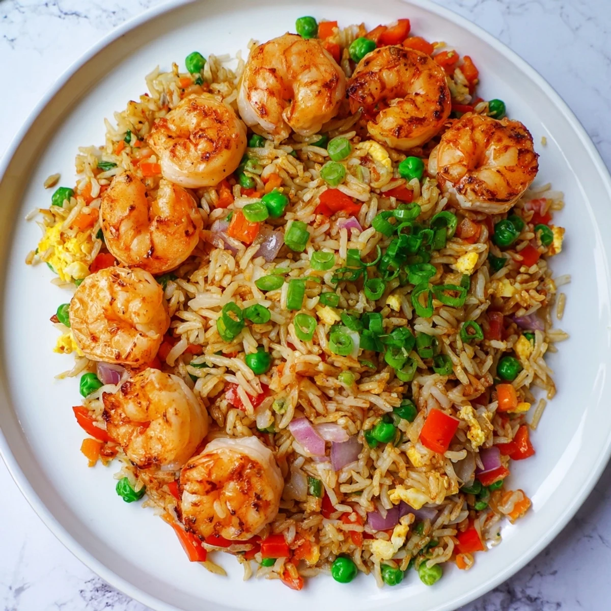 Plated garlic prawns and sweet chilli fried rice garnished with fresh spring onion slices