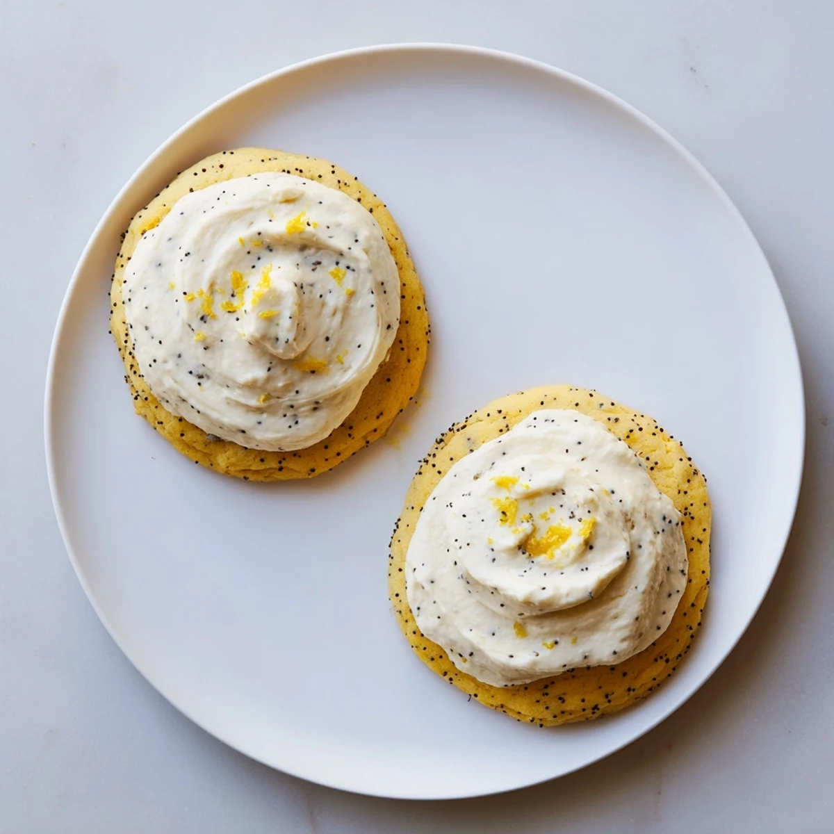 Buttery lemon poppy seed cookies piped with fluffy cheesecake frosting and extra poppy seeds