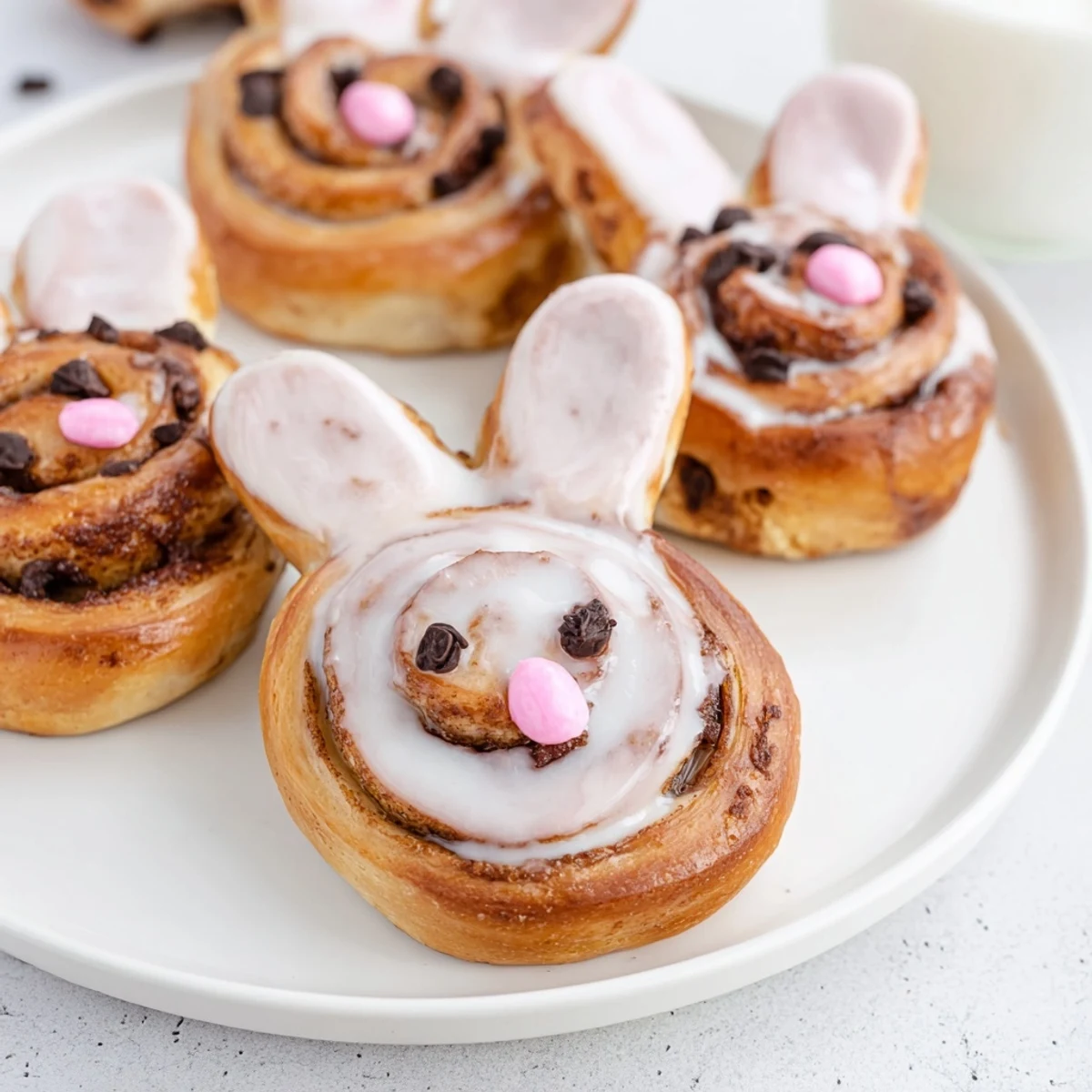 Warm freshly baked Easter Bunny cinnamon rolls with sweet glaze and cute ear shapes arranged on parchment paper for spring breakfast