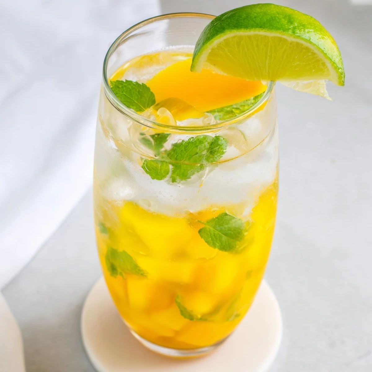 Refreshing summer mango ginger mocktail served over ice with fruit slice garnish