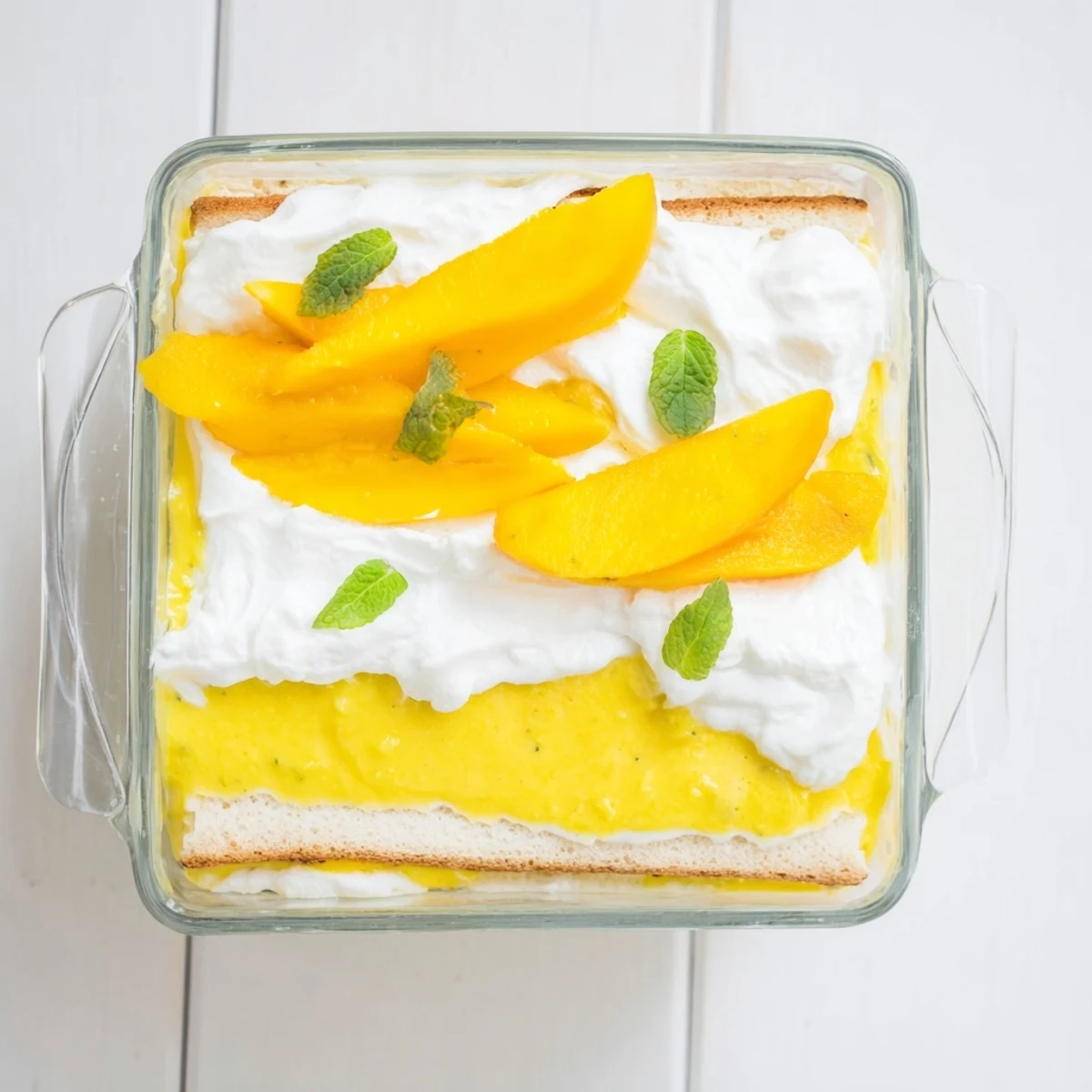 Golden mango tiramisu layered with creamy mascarpone and coffee-soaked ladyfingers in a glass dish