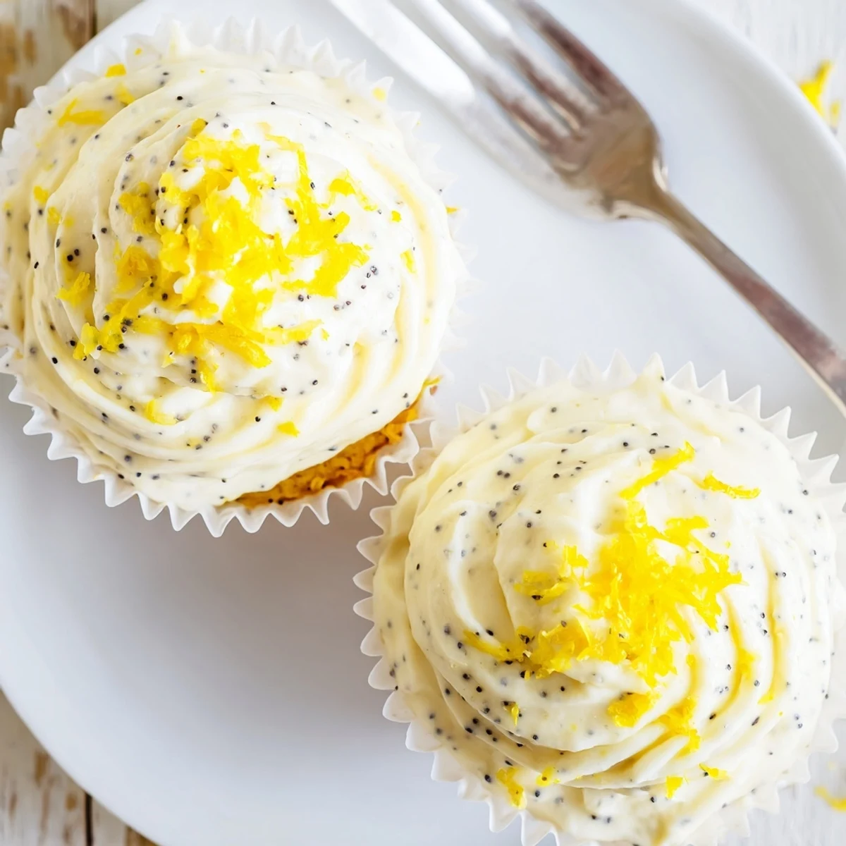 Golden lemon poppy seed cupcakes topped with swirls of creamy lemon cream cheese frosting and sprinkled with fresh lemon zest