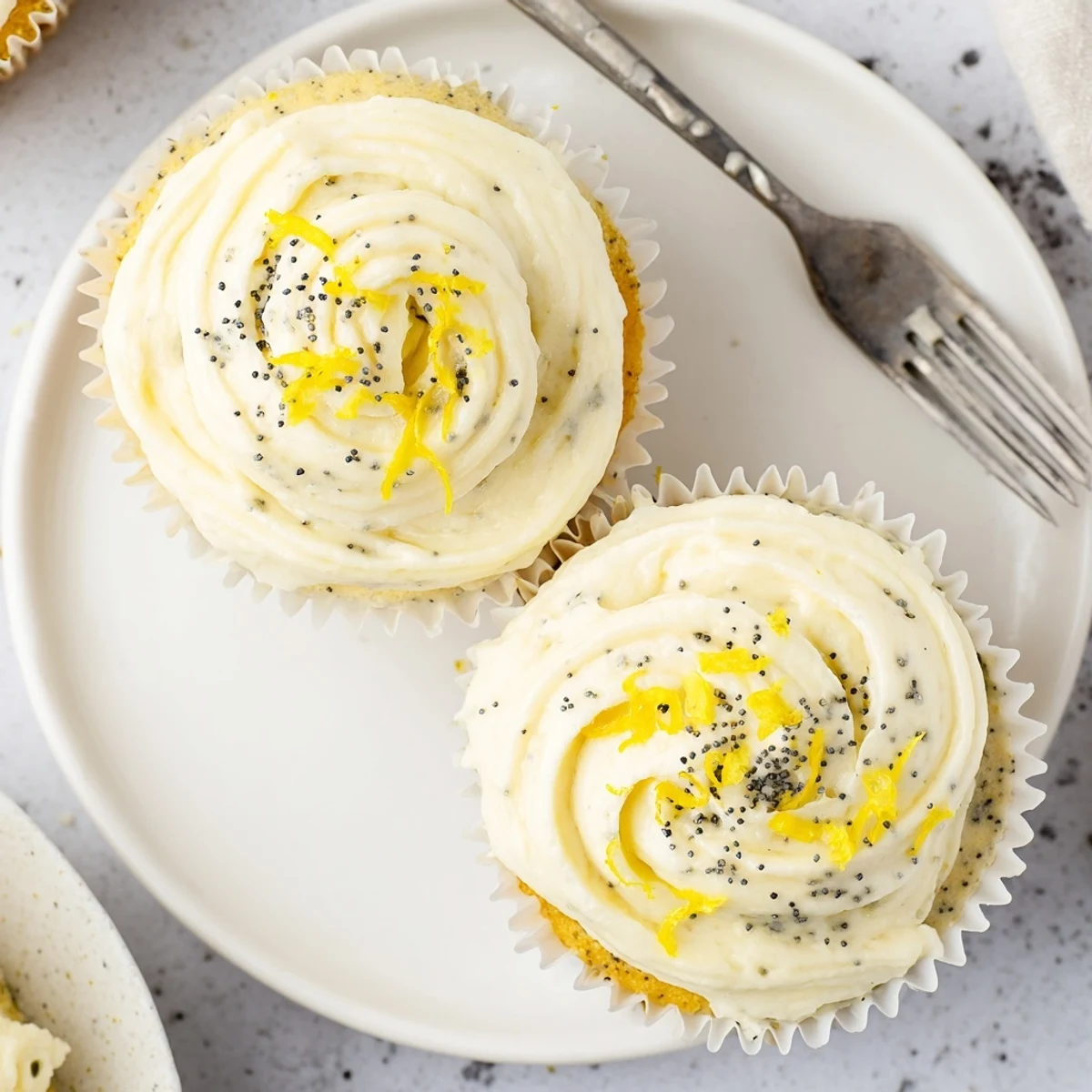 Moist lemon poppy seed cupcakes with tangy citrus flavor and crunchy poppy seeds beneath a thick layer of bright lemon frosting