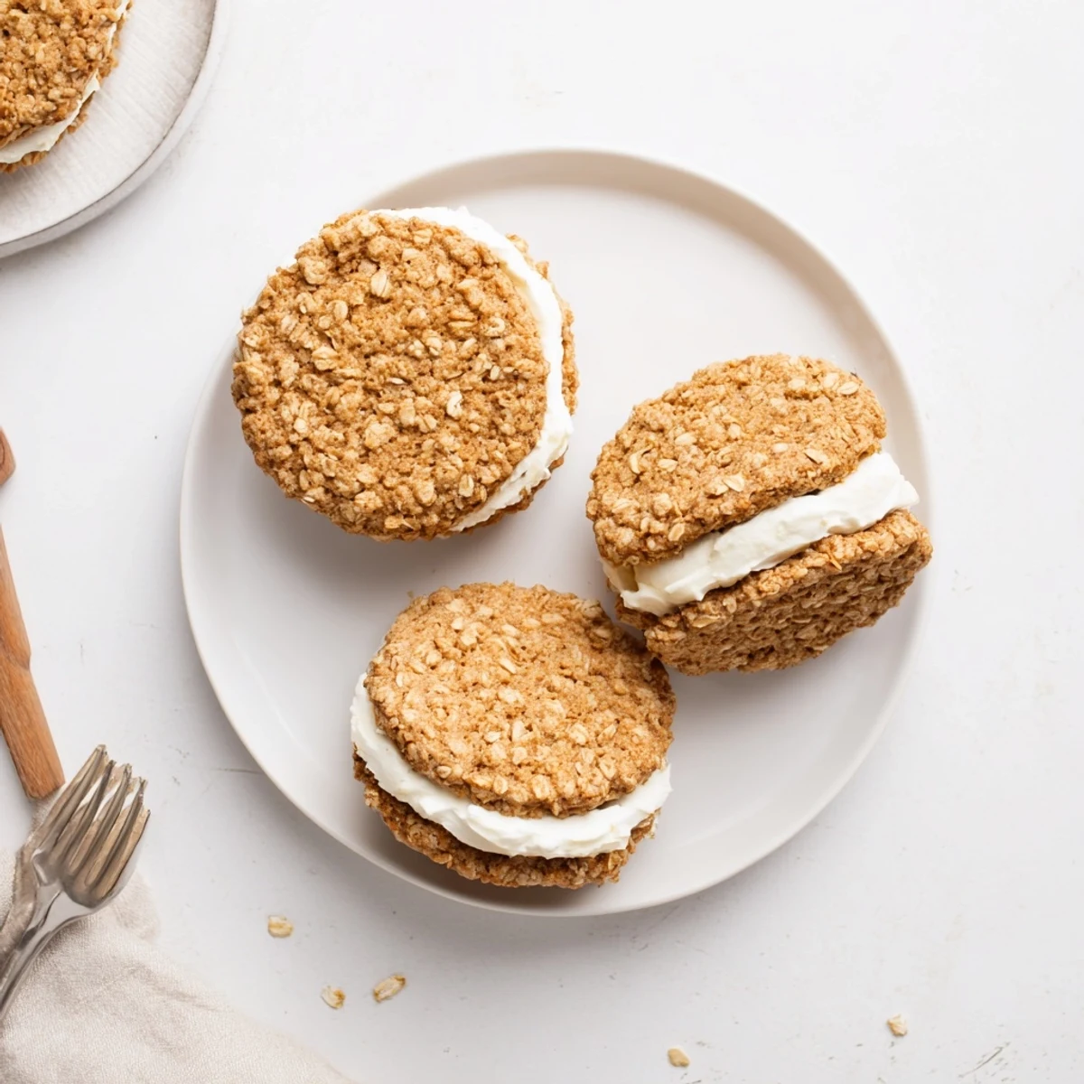 Two soft homemade oatmeal cream pies with vanilla frosting spilling from the sides