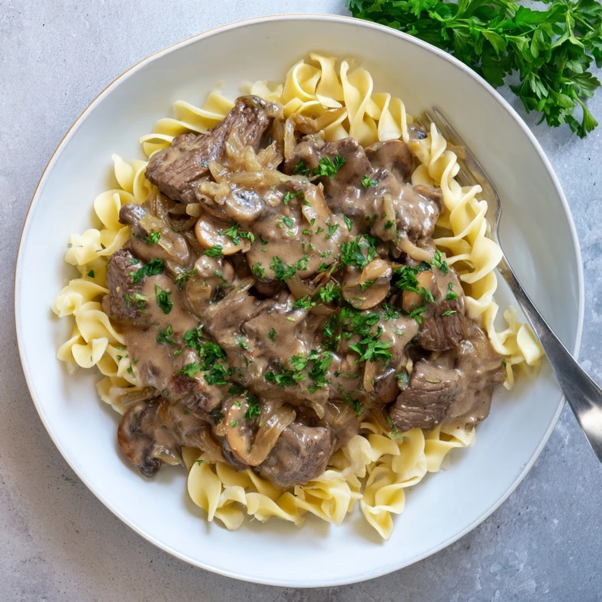Classic beef stroganoff featuring seared beef strips in a velvety white sauce garnished with chopped parsley