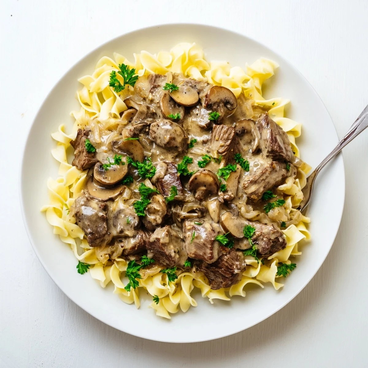 Golden beef stroganoff served in a rich sour cream mushroom sauce alongside steaming white rice
