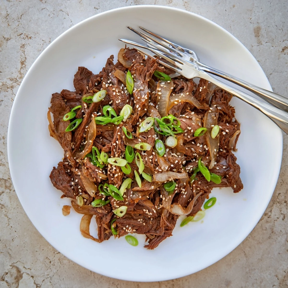 Tender slow cooker Korean beef shredded in rich savory-sweet sauce with sesame seed garnish