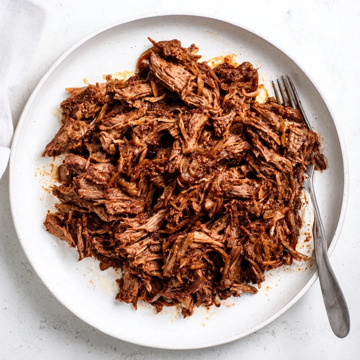 Seasoned slow cooker shredded beef piled high with aromatic onions and juices