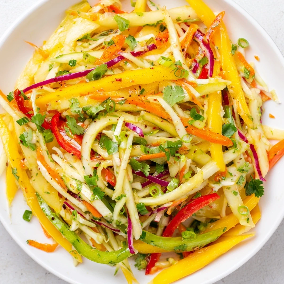 Vibrant mango slaw bowl featuring julienned mango and red cabbage topped with cilantro