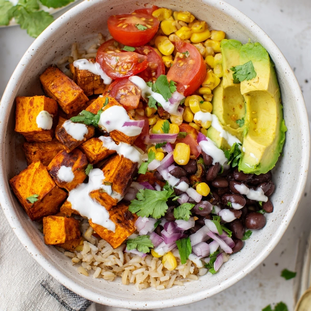 Hearty plant-based vegan sweet potato burrito bowl featuring tender roasted sweet potatoes, fluffy rice, seasoned beans and zesty lime-garnished toppings