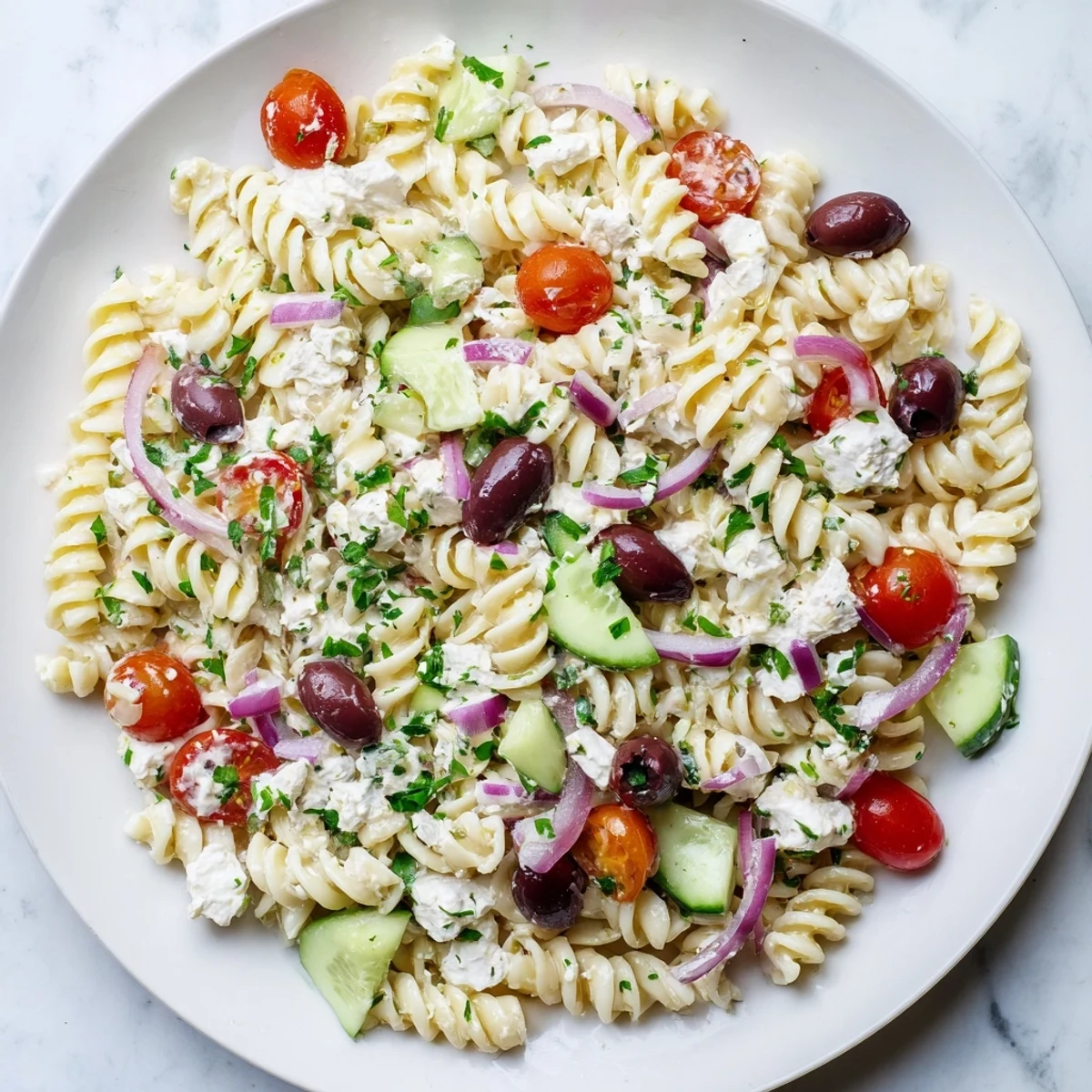 Colorful Mediterranean cottage cheese pasta salad tossed with fresh vegetables in a white serving bowl