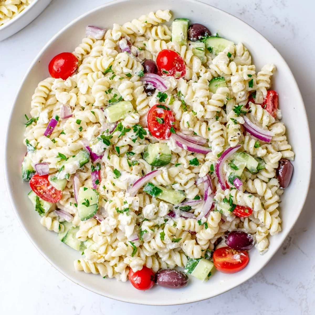 Protein-packed Mediterranean cottage cheese pasta salad featuring cherry tomatoes, cucumber, and olives on a rustic wooden table
