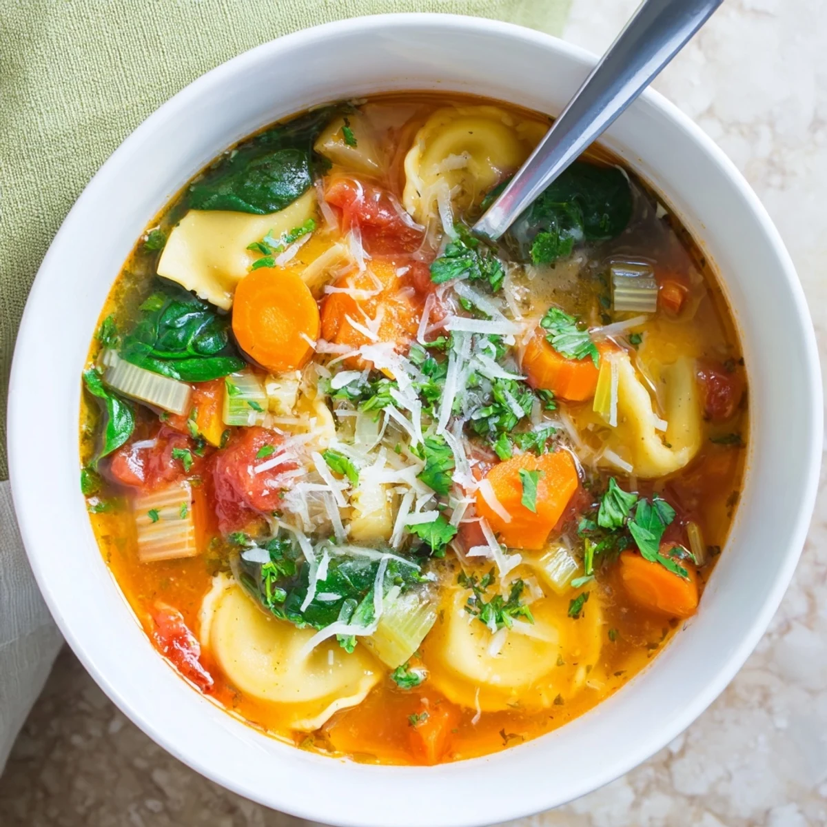 Steaming bowl of Easy Tuscan Ravioli Soup with tender cheese ravioli floating in rich tomato broth alongside fresh spinach