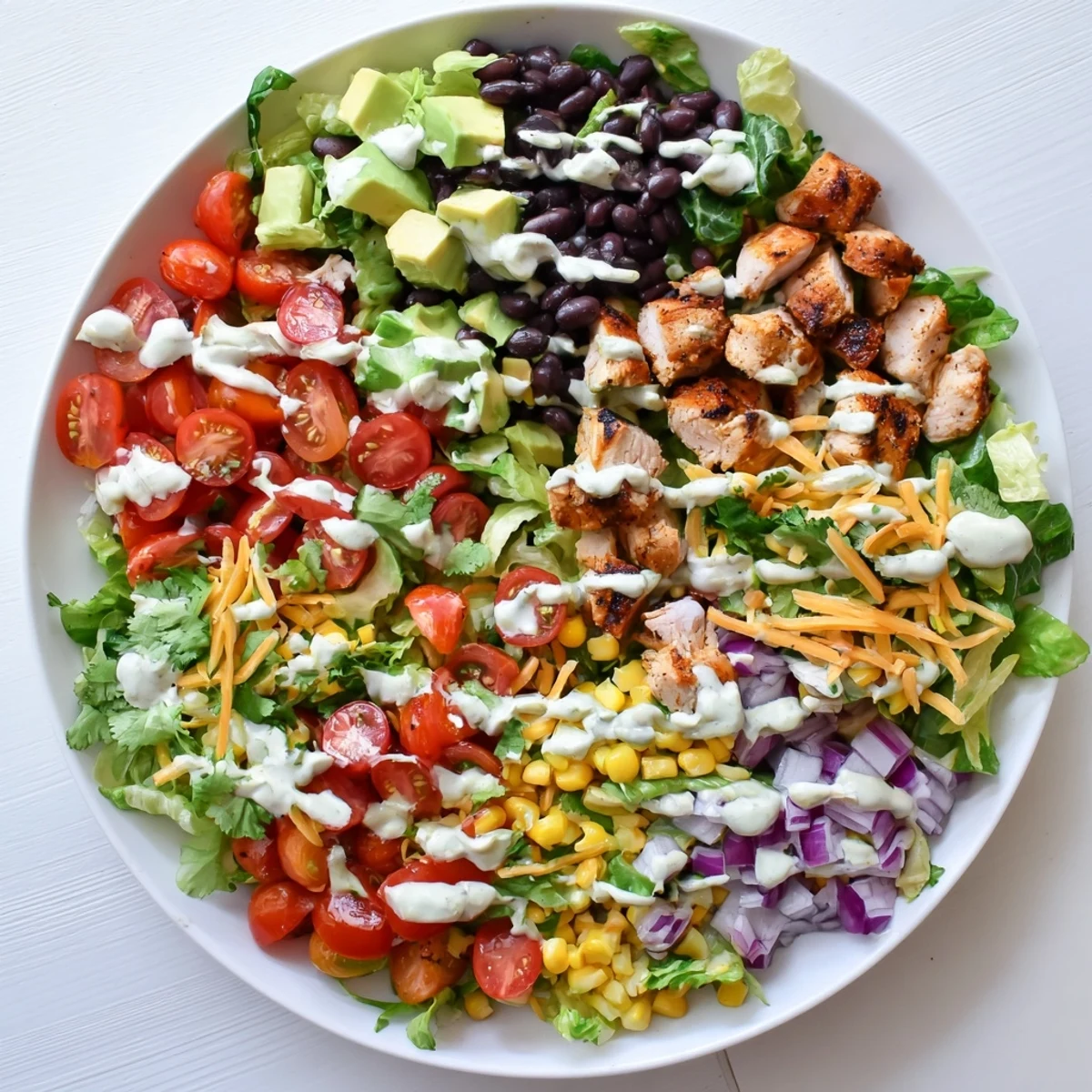 Protein-packed healthy BBQ chicken chopped salad featuring tender grilled chicken pieces, fresh avocado, red bell pepper, and shredded cheddar cheese over a bed of romaine lettuce