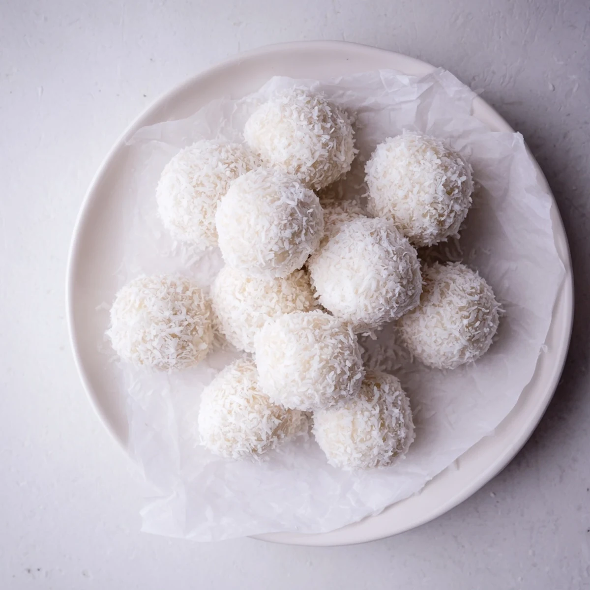 Soft sweetened coconut balls rolled in powdered sugar arranged on a festive Easter serving platter