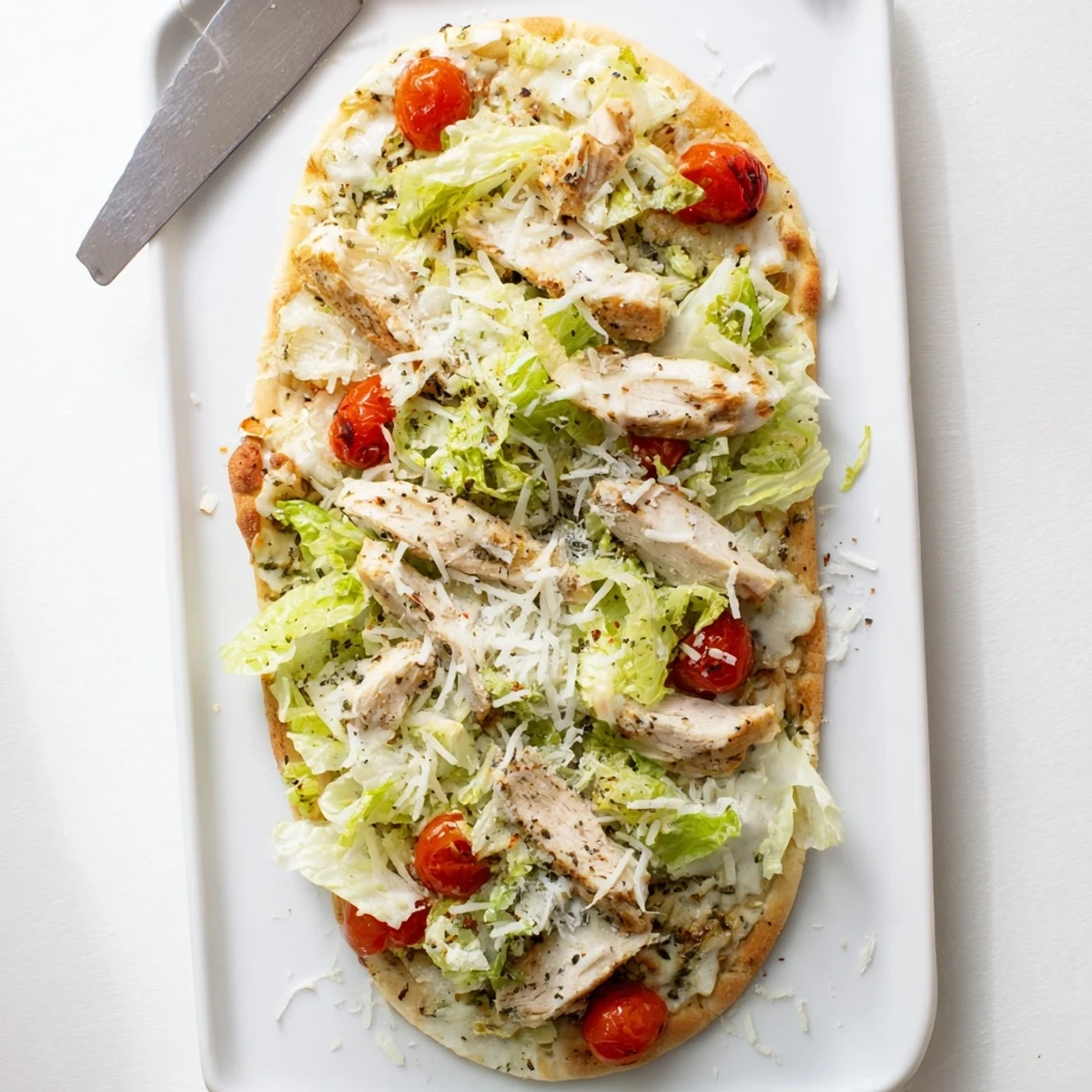 Golden chicken Caesar flatbread topped with melted mozzarella, crisp romaine lettuce, and shaved parmesan cheese