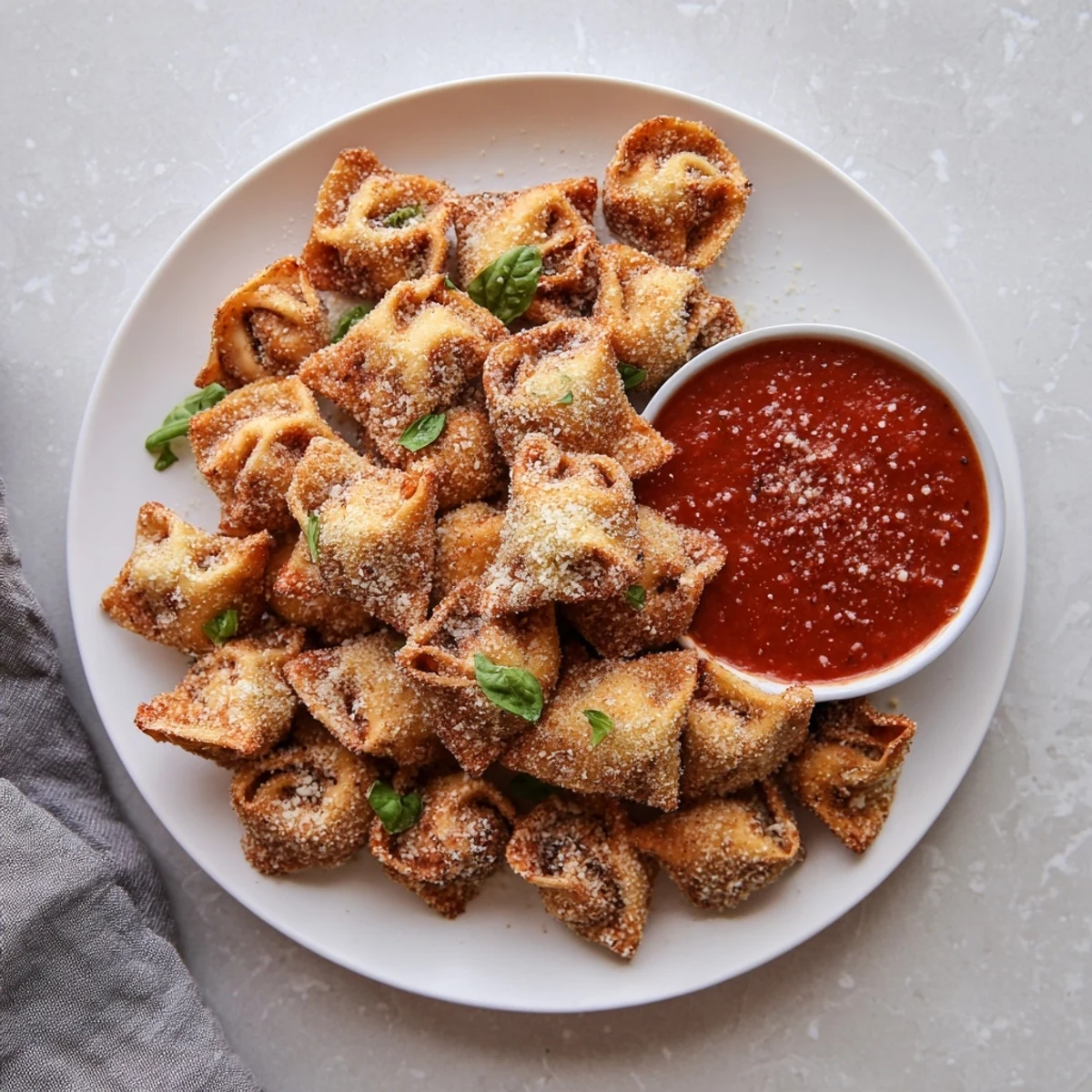 Golden Air Fryer Tortellini arranged on a serving platter with a side of warm marinara sauce for dipping