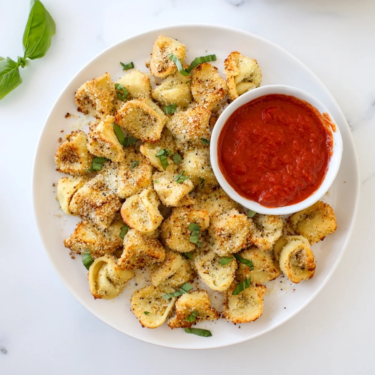 Italian-style Air Fryer Tortellini bites with a golden parmesan breadcrumb coating served on a white plate with herbs