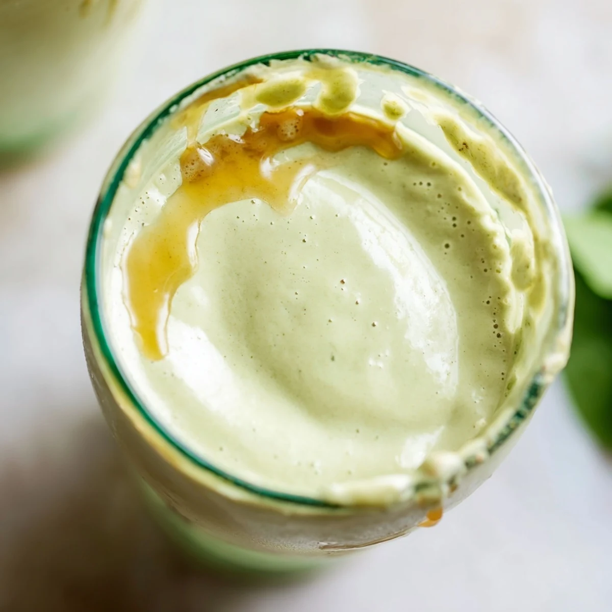 Vibrant Greek yogurt avocado smoothie in a tall glass showing its smooth velvety texture