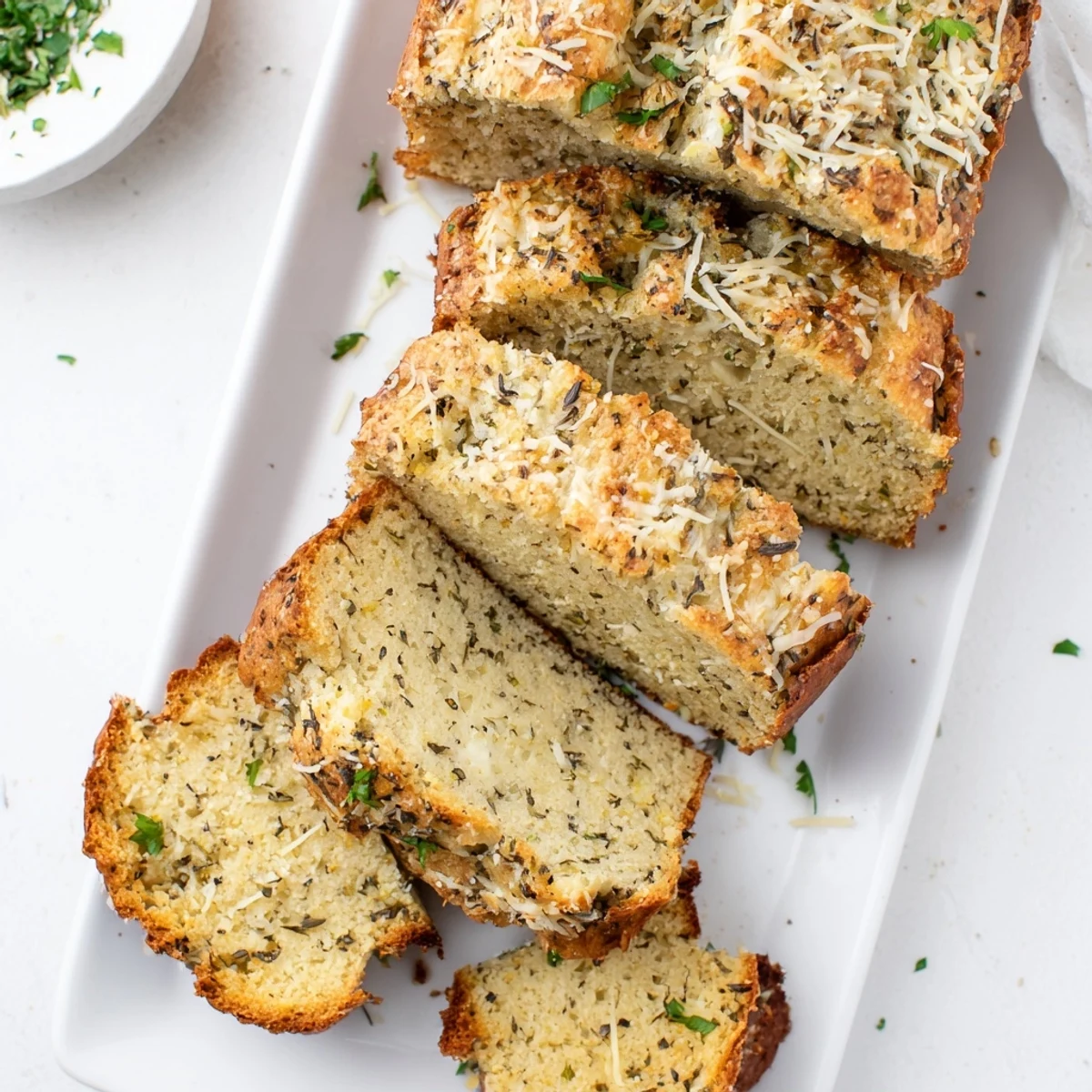 Golden Parmesan herb keto bread loaf topped with melted cheese and fresh parsley garnish