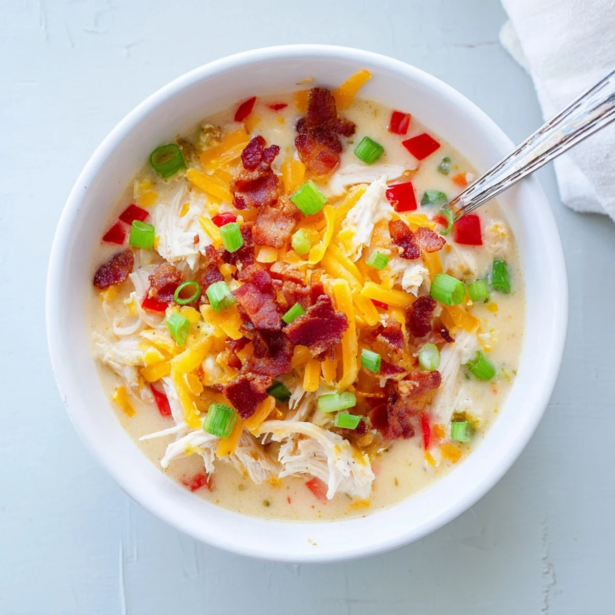 Bowl of Spicy Jalapeno Popper Chicken Soup garnished with fresh green onions and sliced jalapeños