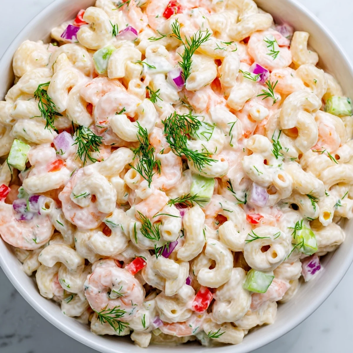 A vibrant scoop of shrimp macaroni salad with red bell pepper and a creamy tangy dressing