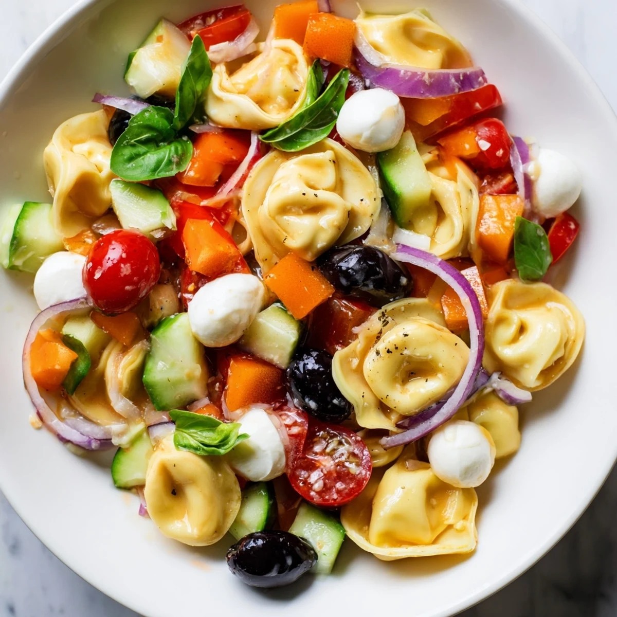 Colorful tortellini salad with crisp vegetables and zesty Italian dressing in a serving bowl