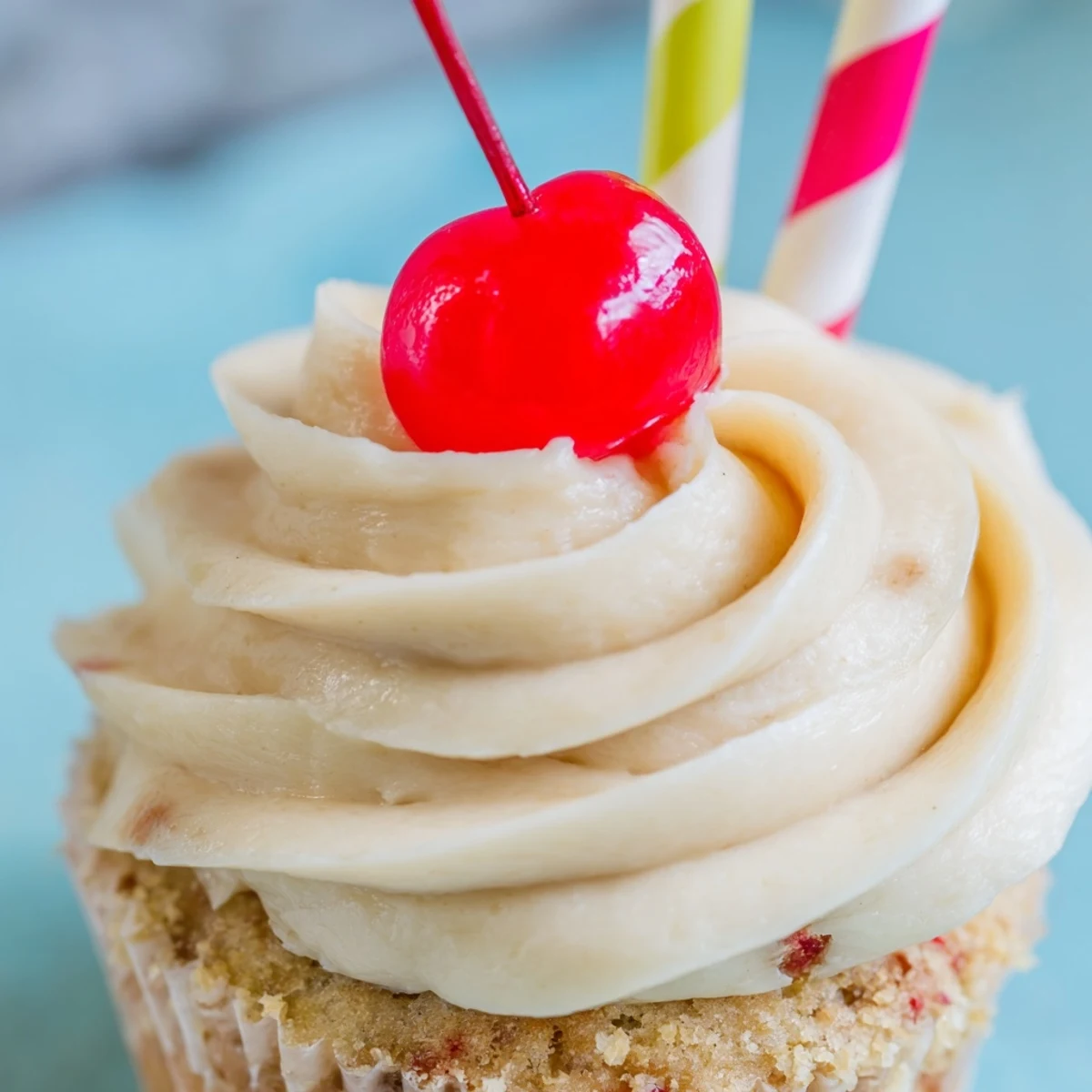 Moist banana milkshake cupcakes topped with creamy vanilla frosting and bright red maraschino cherry garnish