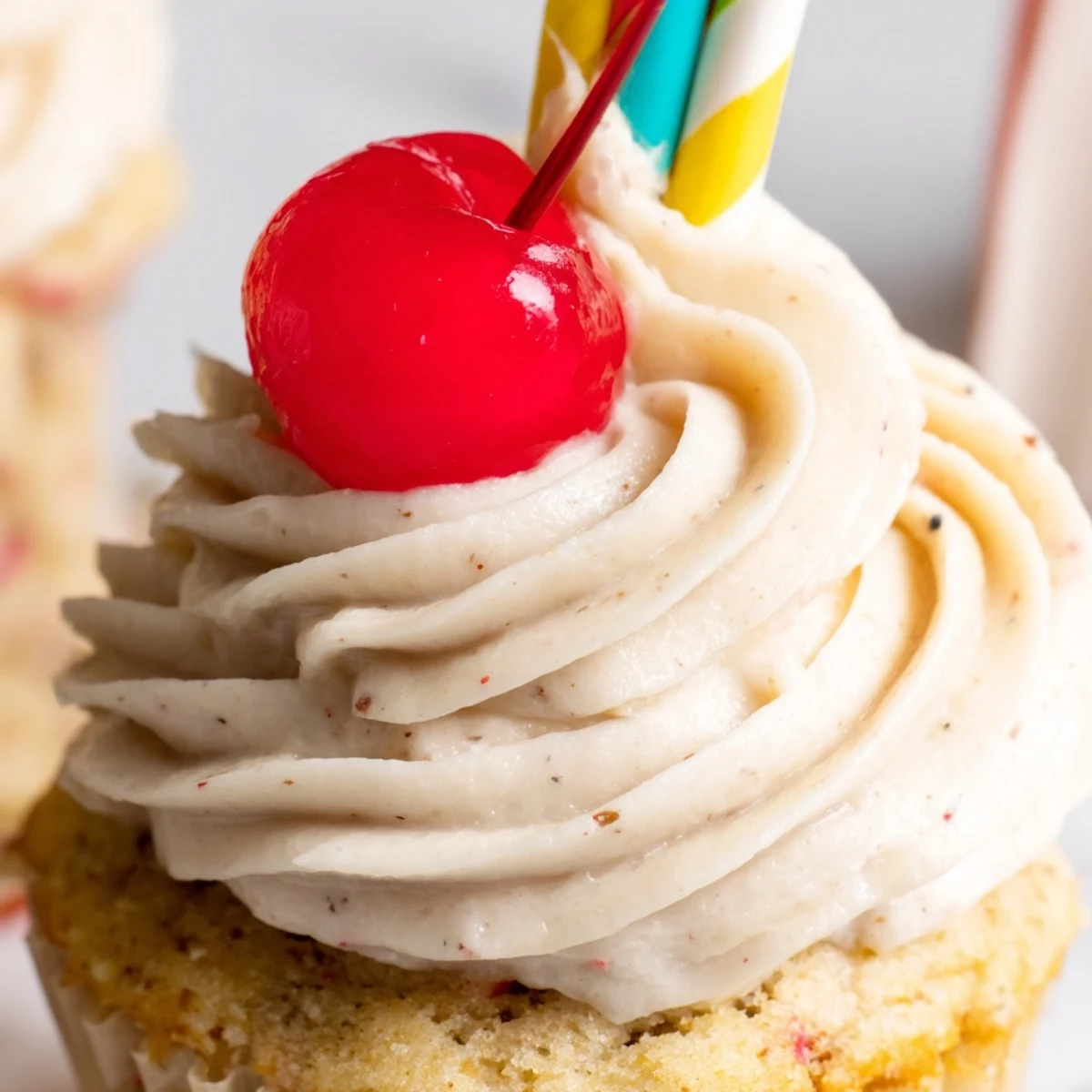 Golden banana milkshake cupcakes with fluffy buttercream swirls served on a rustic white cake stand