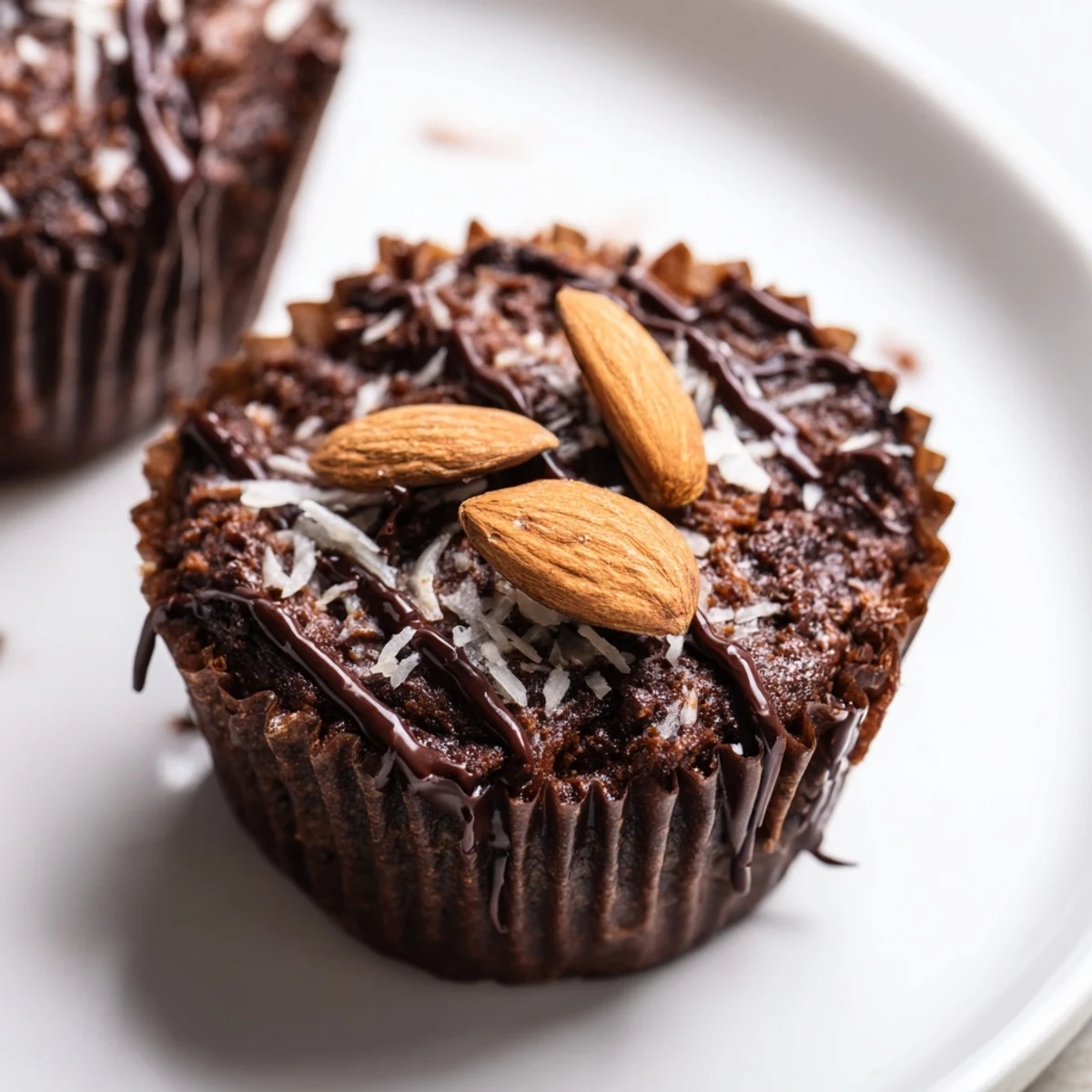 Rich flourless almond joy cupcakes topped with chocolate drizzle and roasted almonds on rustic parchment