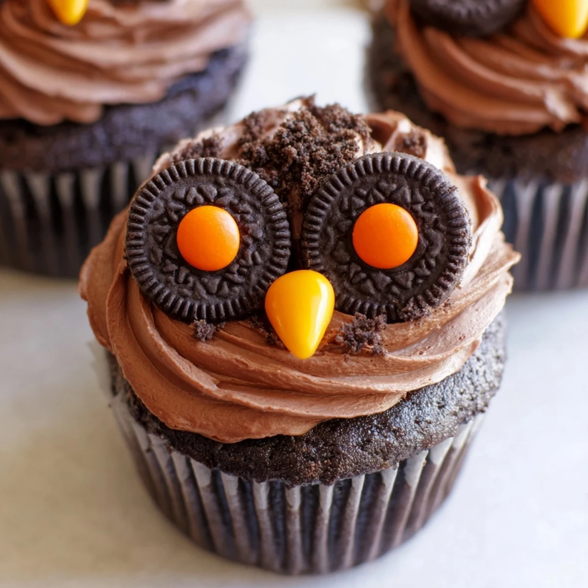 Adorable Oreo owl cupcakes topped with chocolate frosting and candy eyes on a rustic serving tray