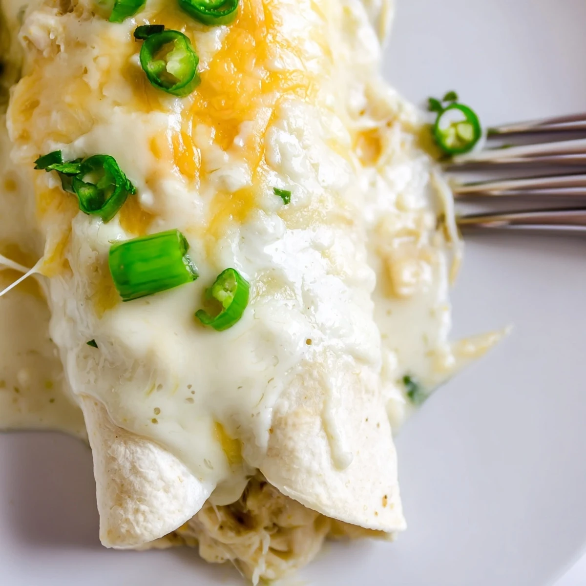 Sliced serving of Creamy White Chicken Enchiladas beside Spanish rice and lime