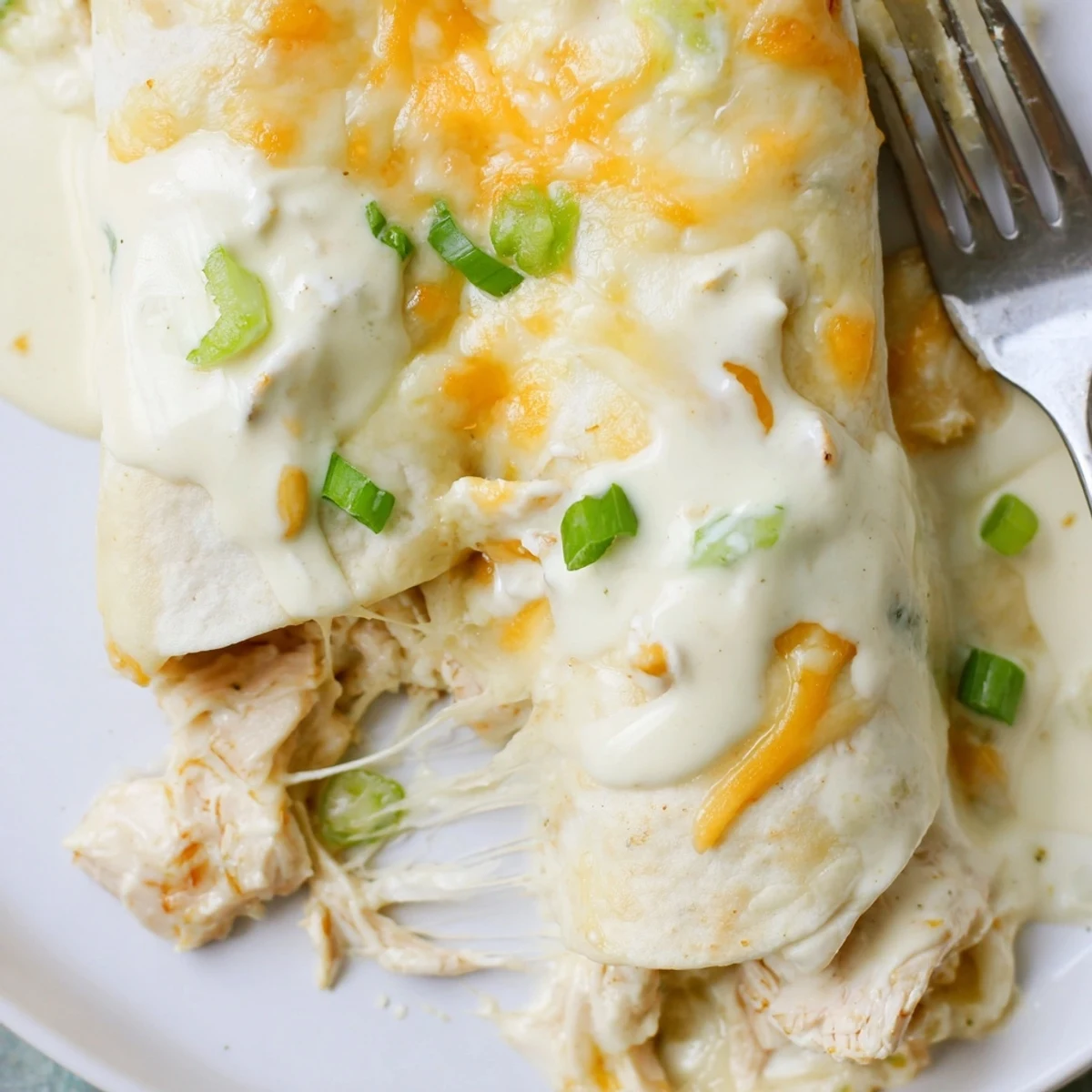 Creamy White Chicken Enchiladas bubbling golden, topped with cilantro and sliced green onions