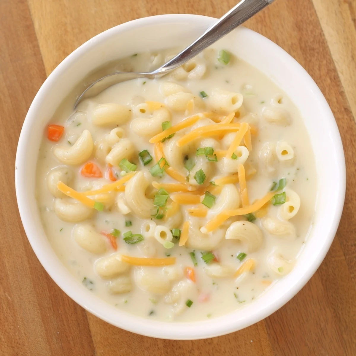 Creamy mac and cheese soup with melted cheddar and elbow pasta in a white bowl