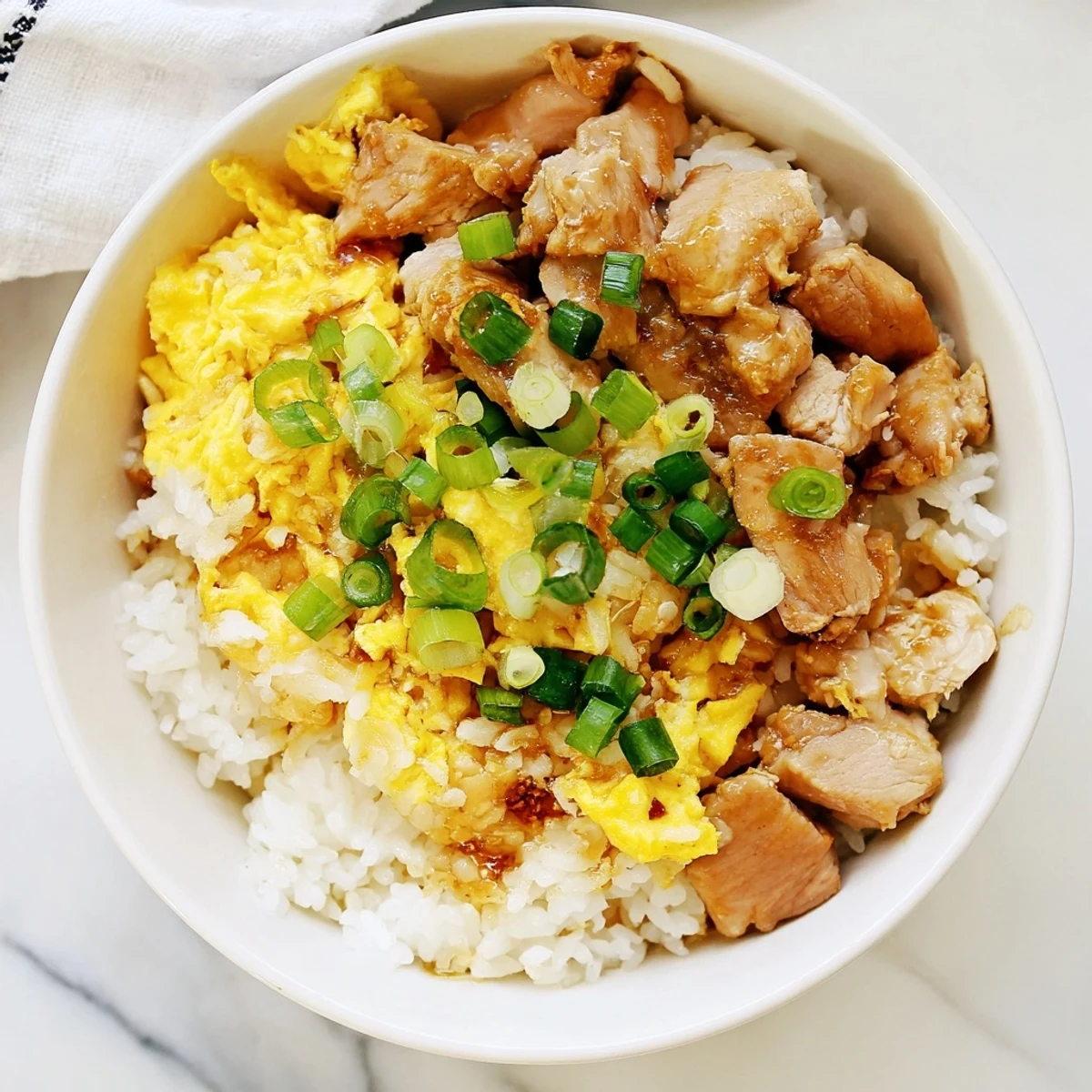 Comforting One Pot Oyakodon with juicy chicken pieces and silky eggs garnished with fresh green onions