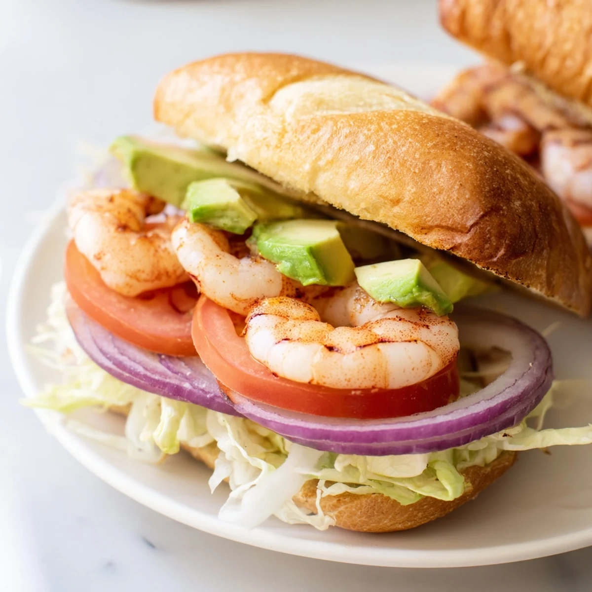 Golden sautéed shrimp sandwich layered with fresh lettuce, tomato, and avocado on toasted brioche roll