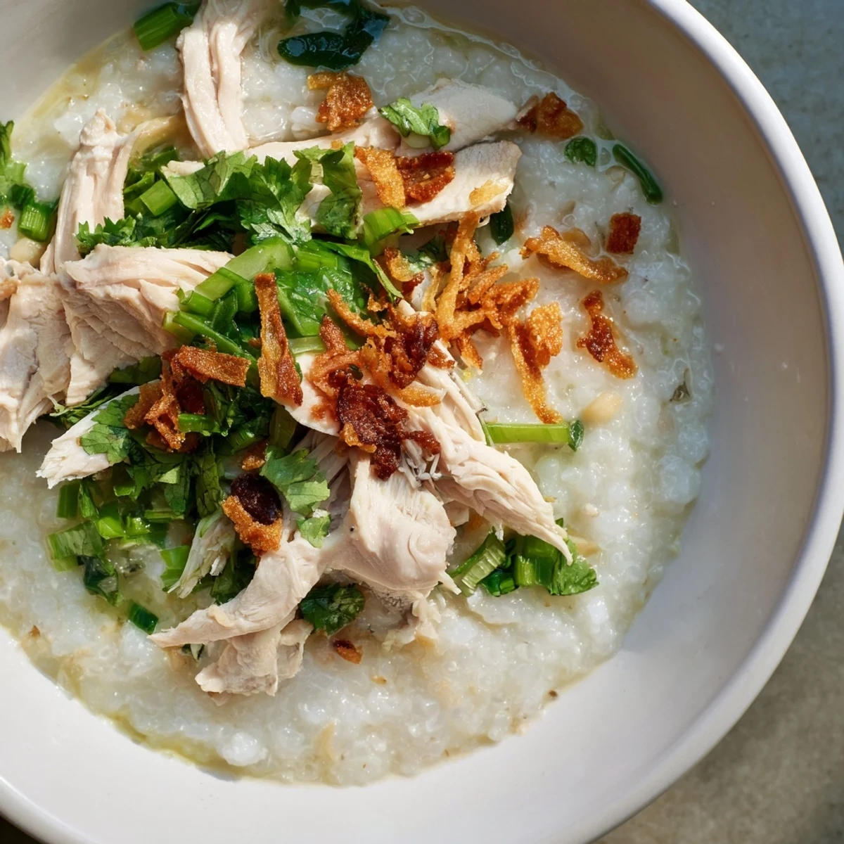 Steaming bowl of Vietnamese chicken rice porridge topped with fresh cilantro and crispy fried shallots