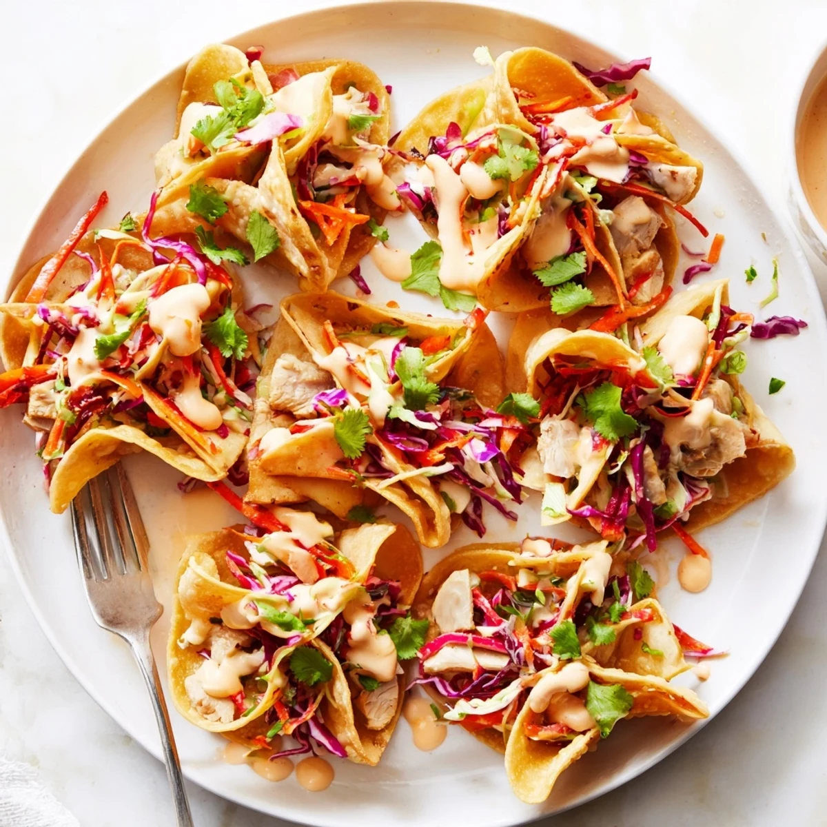 Fusion Asian chicken wonton tacos drizzled with spicy sriracha mayo sauce and topped with fresh cilantro