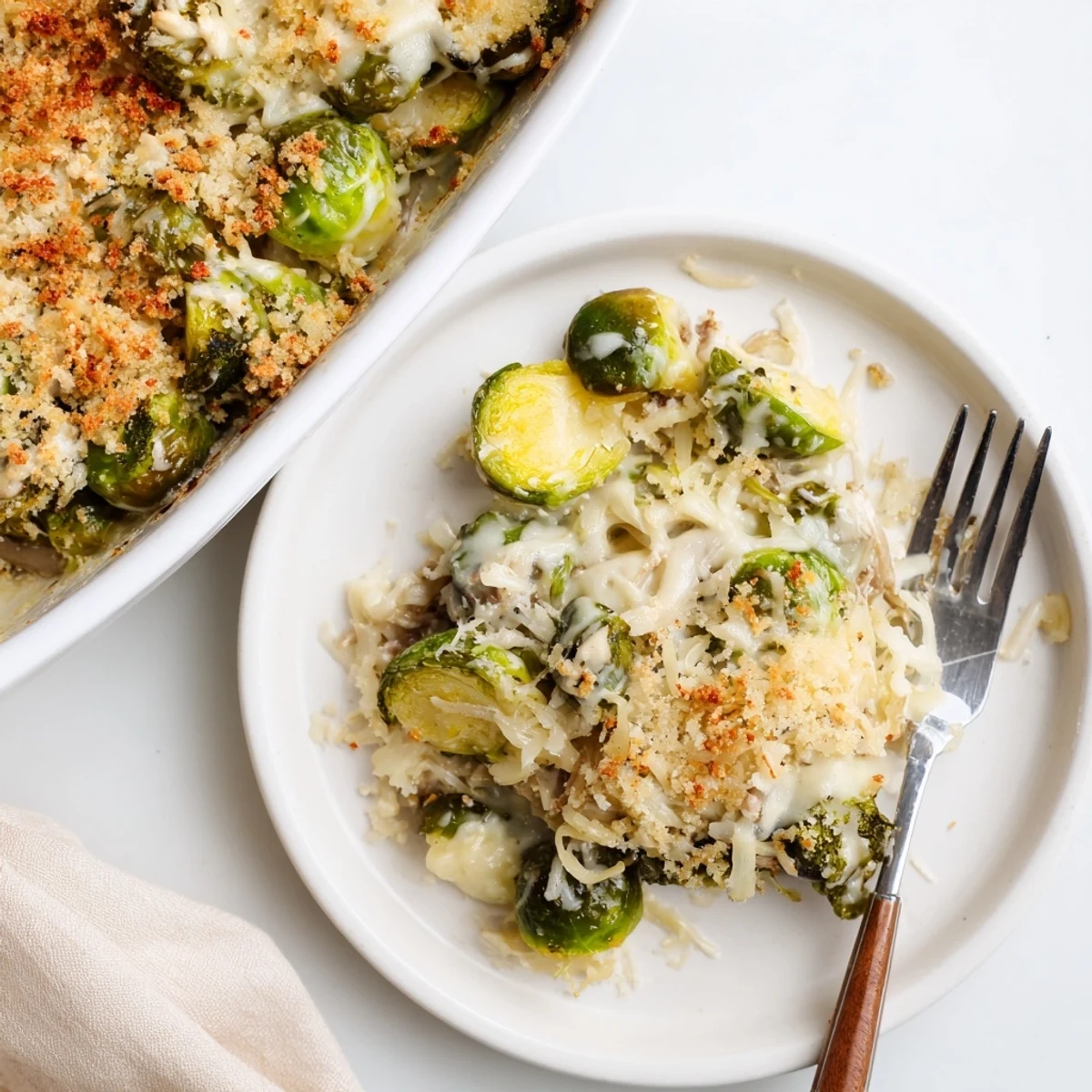 Slice a portion of Creamy Parmesan Brussels Sprouts Casserole beside roasted turkey